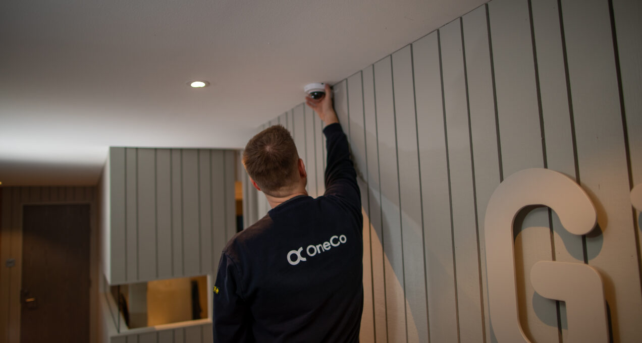 OneCo-tekniker som installerar övervakningskamera i ett tak.